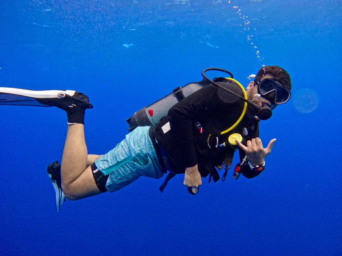 Adesh scuba diving over a reef in open water